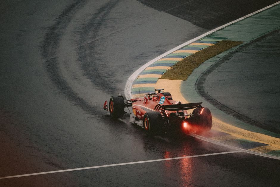Exciting scene of a red race car taking a sharp turn on a wet track, showcasing speed and precision.